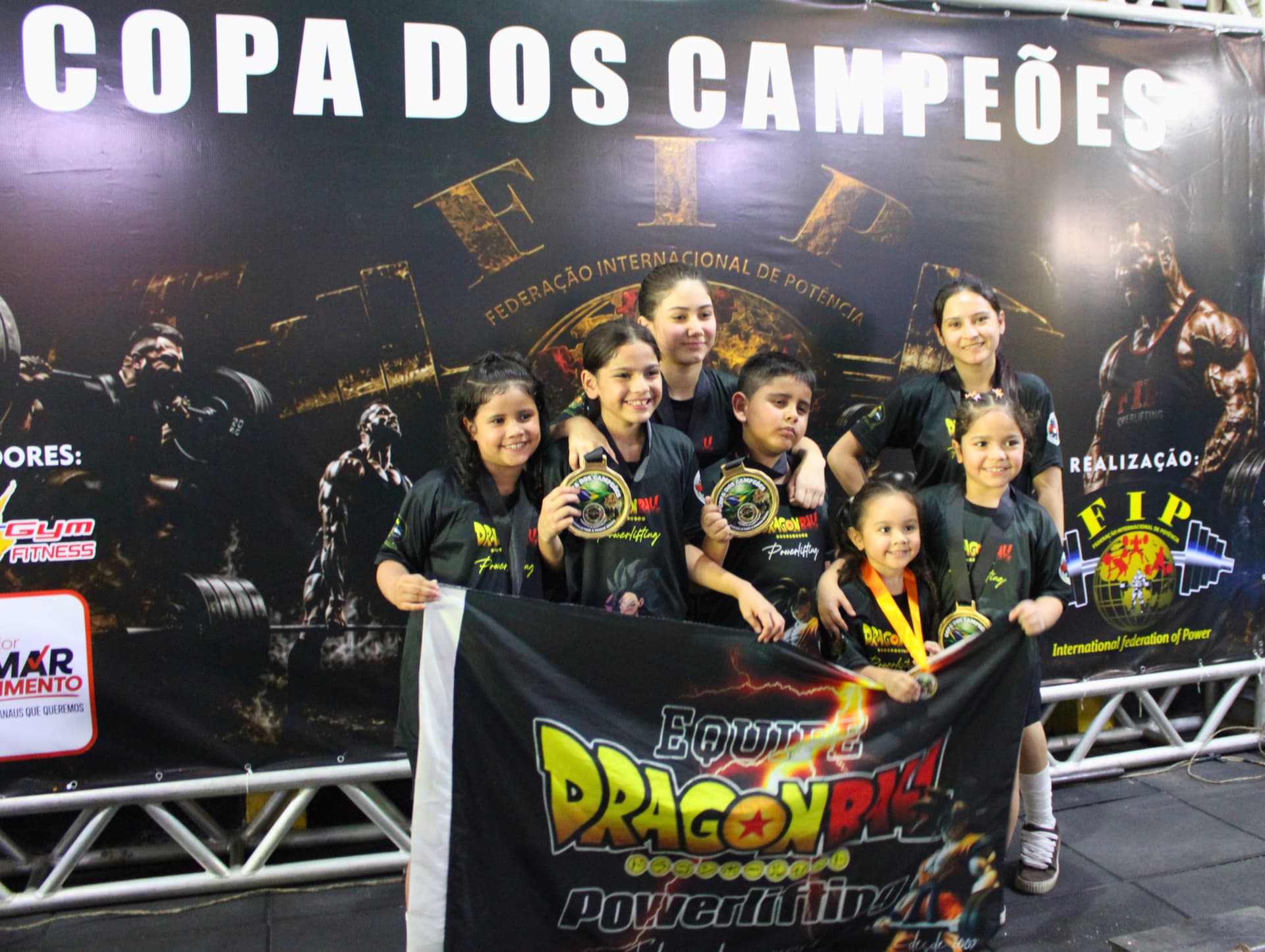 Jovens atletas medalhistas da Copa dos Campeões com a bandeira da equipe